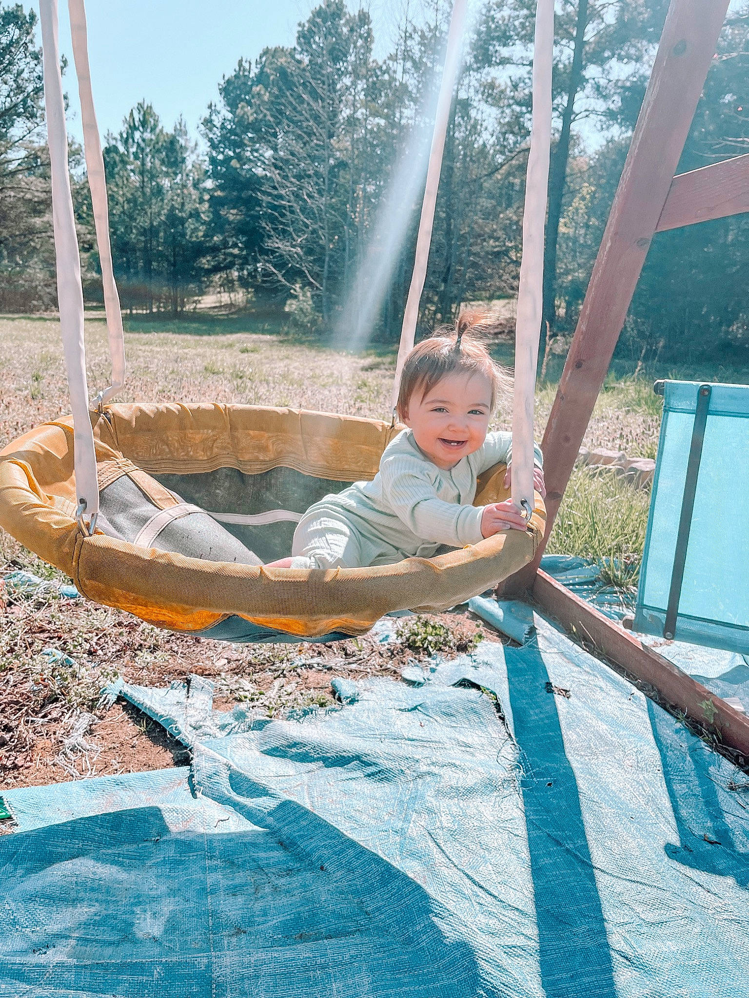 Kingsley is registered to the contest to win money with this photo: boats_and_boating_equipment_and_supplies, camping, fun, grass, hammock, happy, joy, leisure, outdoor_play_equipment, outdoor_recreation, people_in_nature, person, plant, recreation, shade, sitting, sky, swing, toddler, tree