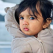 Viyaan is registered to the contest to win money with this photo: child, toddler, face, portrait, jacket, clothing, winter_wear, hair, eyes, expression, outdoor, cold_weather, cute, person, young_child, closeup, warm_clothing, curious, soft_light, head