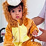 adult_hand, baby, child, clothing, costume, curious, cute, expression, eyes, face, fur, hand, home, indoor, lion_costume, person, portrait, sitting, soft_texture, toddler