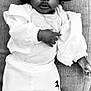 baby, child, black_and_white, hat, couch, clothing, portrait, indoor, infant, sitting, face, cute, young_child, fashion, person, expression, cozy, accessory, relax, closeup