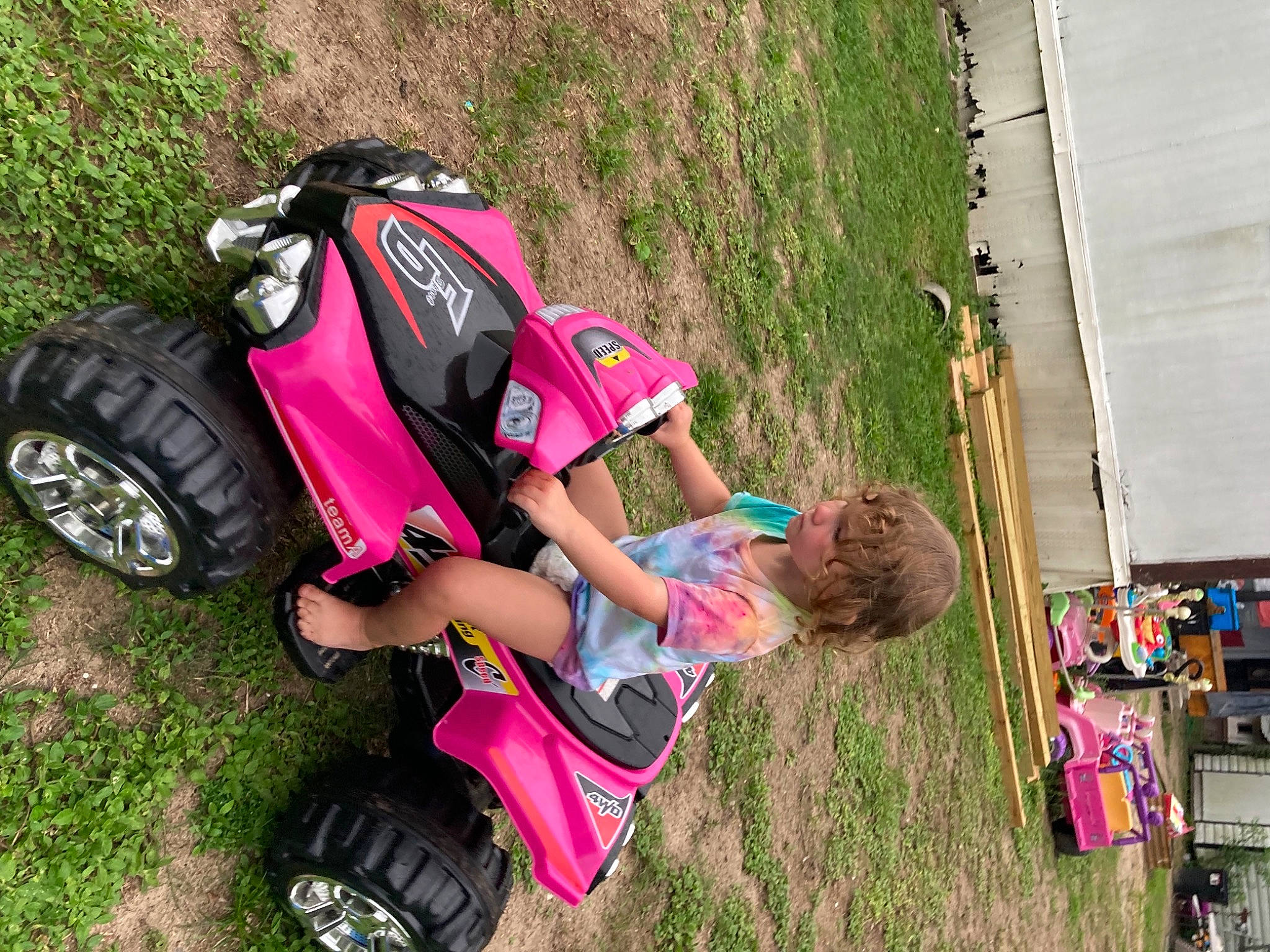 Delilah Evelyn Damron is registered to the contest to win money with this photo: automotive_design, automotive_exterior, automotive_tire, automotive_wheel_system, fender, fun, grass, leisure, motor_vehicle, people_in_nature, person, pink, plant, recreation, rim, synthetic_rubber, tire, toddler, tread, vehicle