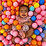 Hailey is registered to the contest to win money with this photo: baby, child, ball_pit, colorful_balls, pink, orange, blue, yellow, smiling, happy, infant, playful, cute, indoors, person, clothing, fun, joy, small_child, portrait