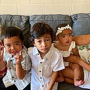 Hailey is registered to the contest to win money with this photo: child, baby, toddler, couch, pillow, white_shirt, headband, person, indoor, family, smile, curly_hair, short_hair, sitting, hand_gesture, arm, skin, young_children, casual_clothing, cozy