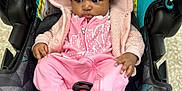 Londyn is registered to the contest to win money with this photo: baby, child, pink_clothing, hooded_jacket, car_seat, indoor, infant, cute, cozy, patterned, footed_pajamas, curious, small_hands, black_hair, fabric_texture, seatbelt, soft_material, casual, young, portrait