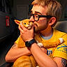 man, glasses, beard, yellow_shirt, tattoo, watch, orange_cat, cat, pet, indoor, chair, affection, hug, kiss, fur, animal, portrait, warm_lighting, close_up, love
