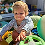 toddler, child, baby, outdoor, toy, steering_wheel, grass, sunlight, play, cute, curly_hair, onesie, hand, face, expression, daylight, garden, fun, colorful, young_child