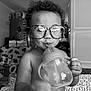 Bentley is registered to the contest to win money with this photo: toddler, child, glasses, sippy_cup, curly_hair, indoors, blanket, baby, cute, drinking, face, expression, hand, sitting, home, black_and_white, portrait, person, young_child, cozy