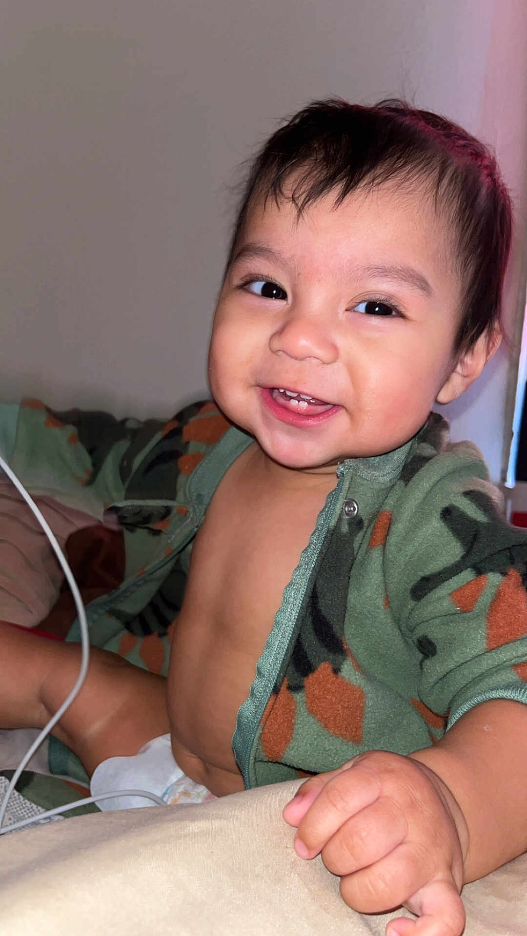 Alexander is registered to the contest to win money with this photo: baby, smiling, child, face, hand, diaper, clothing, jacket, camo, cute, happy, indoors, person, portrait, toddler, skin, young, expression, sitting, chubby