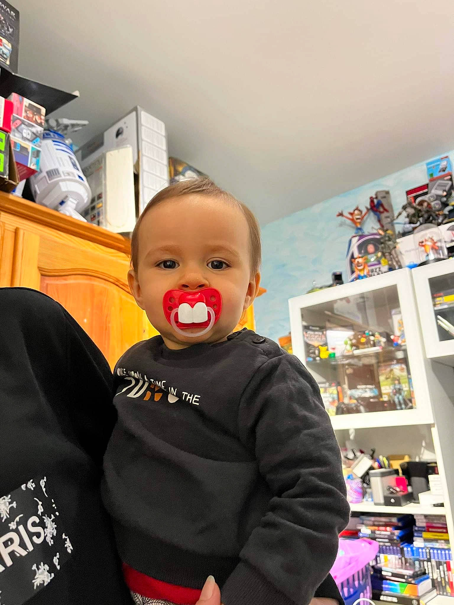 Giulio participe au concours pour gagner de l'argent avec cette photo : baby, baby_products, bookcase, building, child, event, fictional_character, flooring, fun, person, personal_protective_equipment, refrigerator, retail, room, service, shelf, shelving, sleeve, t_shirt, toddler