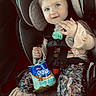 toddler, child, car_seat, pacifier, snack, graham_crackers, cinnamon, headband, blue_eyes, clothing, seatbelt, car_interior, cute, baby, sitting, smile, young_child, indoor, portrait, safety