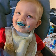 Janet is registered to the contest to win money with this photo: baby, bib, blue_food, child, cute, face, feeding_time, food_stains, happy, high_chair, indoor, messy, playful, portrait, red_shirt, seat, smile, straps, toddler, young_child