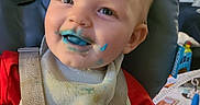 Janet is registered to the contest to win money with this photo: baby, bib, blue_food, child, cute, face, feeding_time, food_stains, happy, high_chair, indoor, messy, playful, portrait, red_shirt, seat, smile, straps, toddler, young_child