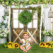 Saanjh is registered to the contest to win money with this photo: baby, child, toddler, portrait, smiling, sitting, outdoor, garden, flowers, sunflowers, plants, greenery, floral, nature, decor, birdcage, lantern, rustic, yellow_headband, festive