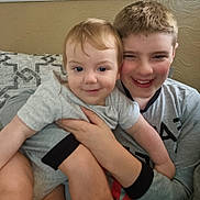 James joined the competition — help win amazing prizes! baby, boy, casual, child, clothing, couch, cute, face, family, happy, head, holding, hug, indoor, person, portrait, sibling, smiling, toddler, young