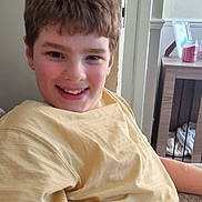 James is registered to the contest to win money with this photo: boy, candle, casual, child, couch, face, furniture, hair, happy, home, indoor, person, photo_frame, portrait, relaxing, sitting, smile, table, yellow_shirt, young