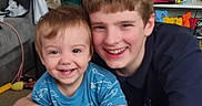 James is registered to the contest to win money with this photo: background, boy, candid, casual, child, clothing, couch, face, family, hair, happy, indoor, living_room, person, portrait, sibling, smiling, toddler, toy, young