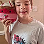 child, smiling, plush_toy, dessert, tshirt, marvel, superhero, indoor, person, face, hand, light_switch, wall, short_hair, casual_clothing, happy, portrait, cute, toy, standing