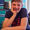 child, smiling, portrait, indoor, cat, home, furniture, desk, computer, speaker, window, colorful, short_hair, t_shirt, blue_shorts, seated, hand_on_cheek, happy, face, photography