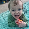 baby, child, smiling, indoor, toy, orange_ball, rug, fluffy_rug, green_clothing, happy, face, eyes, hands, mouth, teeth, carpet, floor, person, cute, infant