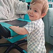Orlando joined the competition — help win amazing prizes! toddler, child, smiling, checkered_clothing, gaming_chair, blanket, indoor, carpet, furniture, person, baby, happy, standing, blue, black, technology, monitor, cozy, home, cute