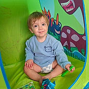 Orlando joined the competition — help win amazing prizes! toddler, child, smiling, portrait, sitting, play_tent, colorful, toy, dinosaur, cartoon, indoors, green, blue, shirt, diaper, storybook, snack_bag, cross_legged, happy, face