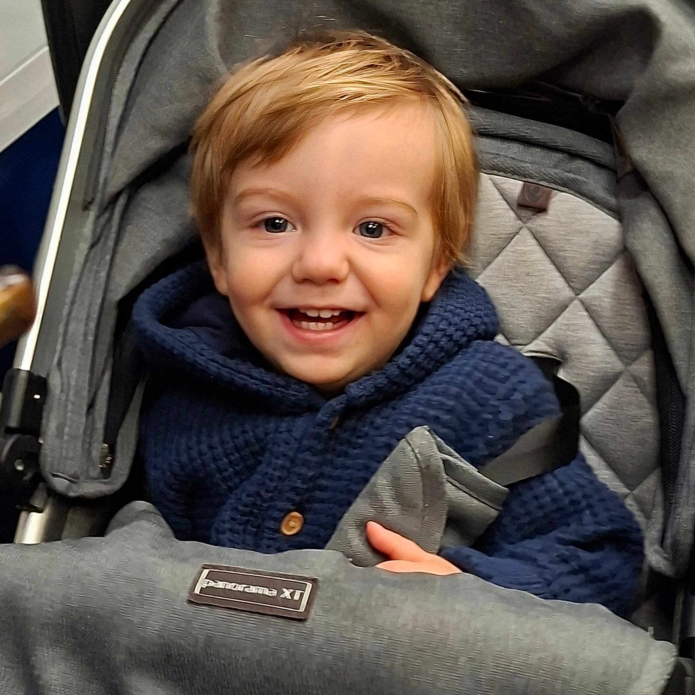 Orlando joined the competition — help win amazing prizes! child, toddler, baby, smiling, happy, portrait, stroller, car_seat, harness, buckled, blue_clothing, hoodie, red_hair, brown_eyes, indoors, close_up, seated, infant, safe, photography
