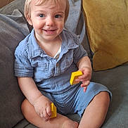 Orlando is registered to the contest to win money with this photo: toddler, child, smiling, blue_eyes, short_hair, blue_shirt, yellow_blocks, couch, gray_cushion, yellow_cushion, indoor, happy, sitting, barefoot, cute, portrait, playful, cozy, home, person