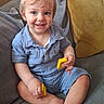 toddler, child, smiling, blue_eyes, short_hair, blue_shirt, yellow_blocks, couch, gray_cushion, yellow_cushion, indoor, happy, sitting, barefoot, cute, portrait, playful, cozy, home, person