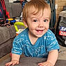 bag, blue_shirt, carpet, child, clothing, couch, door, face, fish_pattern, hair, hands, happy, home, indoor, living_room, person, smiling, toddler, toy, vacuum_cleaner