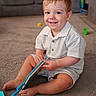 Orlando is registered to the contest to win money with this photo: toddler, child, smiling, book, carpet, indoor, living_room, toy, striped_clothing, barefoot, cute, happy, sitting, person, young_child, play, floor, home, casual, portrait