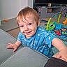 Orlando is registered to the contest to win money with this photo: toddler, child, smile, blue_shirt, indoor, playmat, toy, couch, hand, hair, face, person, carpet, furniture, living_room, cute, expression, happy, skin, play