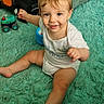 baby, car_toy, child, clothing, colorful, cute, expression, floor, fun, happy, indoor, person, pillow, play, rug, sitting, smile, toddler, toy, young_child