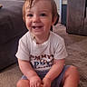 barefoot, carpet, child, cute, expression, furniture, hair, happy, home, indoor, living_room, person, playful, shorts, sitting, smiling, toddler, toy, tshirt, young_child