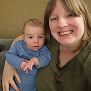 Orlando is registered to the contest to win money with this photo: baby, child, woman, person, smile, face, indoor, couch, clothing, holding, portrait, happy, skin, head, sitting, casual, home, family, blue, green