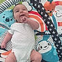 baby, infant, play_mat, toy, colorful, smiling, lying_down, onesie, patterned, soft_toys, cute, child, indoor, happy, small_hands, small_feet, animal_print, playtime, comfort, nursery