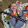 baby, child, blue_pajamas, play_mat, carpet, toy, book, smiling, happy, infant, feet, hands, colorful, indoor, person, cute, playful, floor, patterned, young