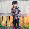 Angel joined the competition — help win amazing prizes! child, boy, standing, colorful_clothing, floral_shirt, spiderweb_pants, sneakers, curly_hair, wooden_fence, metal_wall, grass, outdoor, casual_pose, daylight, nature, yard, portrait, fashion, young, cute