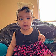 Angely joined the competition — help win amazing prizes! toddler, child, baby, headband, bow, skirt, black_top, sitting, bed, blanket, window, indoors, curious, skin, foot, hand, person, portrait, natural_light, casual