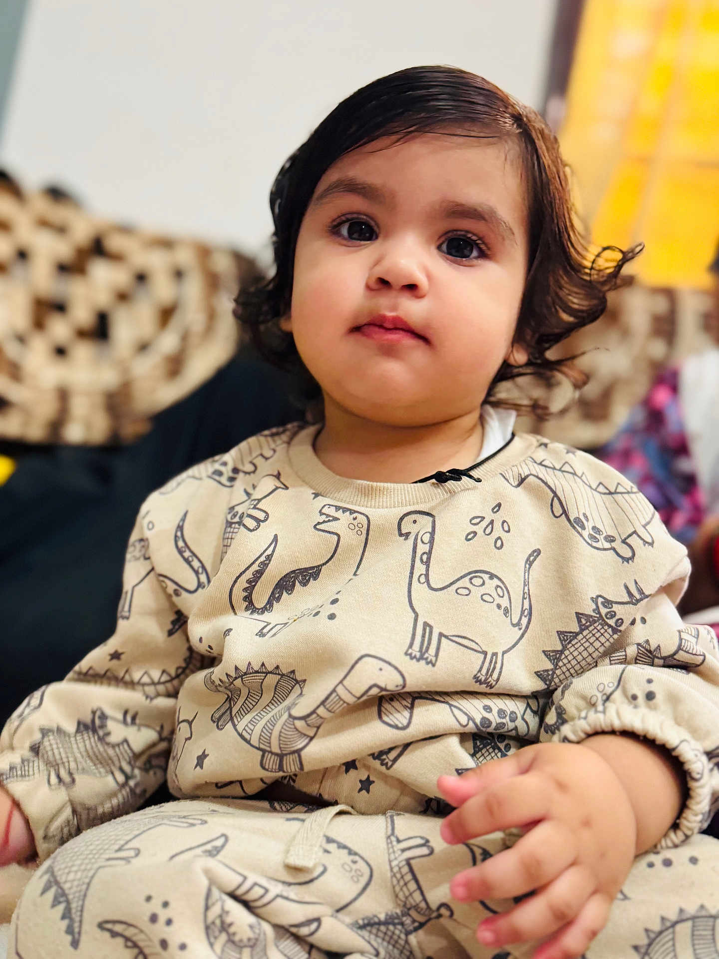 Kevika is registered to the contest to win money with this photo: toddler, child, face, portrait, dinosaur_print, clothing, cute, indoors, sitting, hand, hair, expression, young_child, person, soft_lighting, cozy, patterned_clothes, curly_hair, young, casual