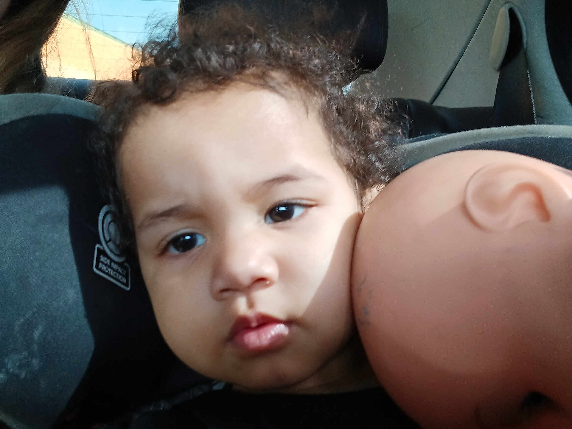 Amiracle joined the competition — help win amazing prizes! toddler, child, car_seat, curly_hair, doll, doll_head, face, portrait, indoors, seat, window, light, shadow, person, baby, expression, headrest, skin, closeup, young_child
