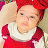 accessory, baby, child, couch, crib_slats, cute, eyes, face, headband, indoors, infant, knitted, lips, pillow, portrait, red_bow, red_dress, relaxed, skin, white_shirt