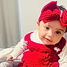 Noore is registered to the contest to win money with this photo: baby, bedding, bedroom, blanket, bow, child, cozy, cute, eyes, face, hand, headband, indoor, infant, knitwear, portrait, red_dress, red_knit, smile, white_long_sleeve