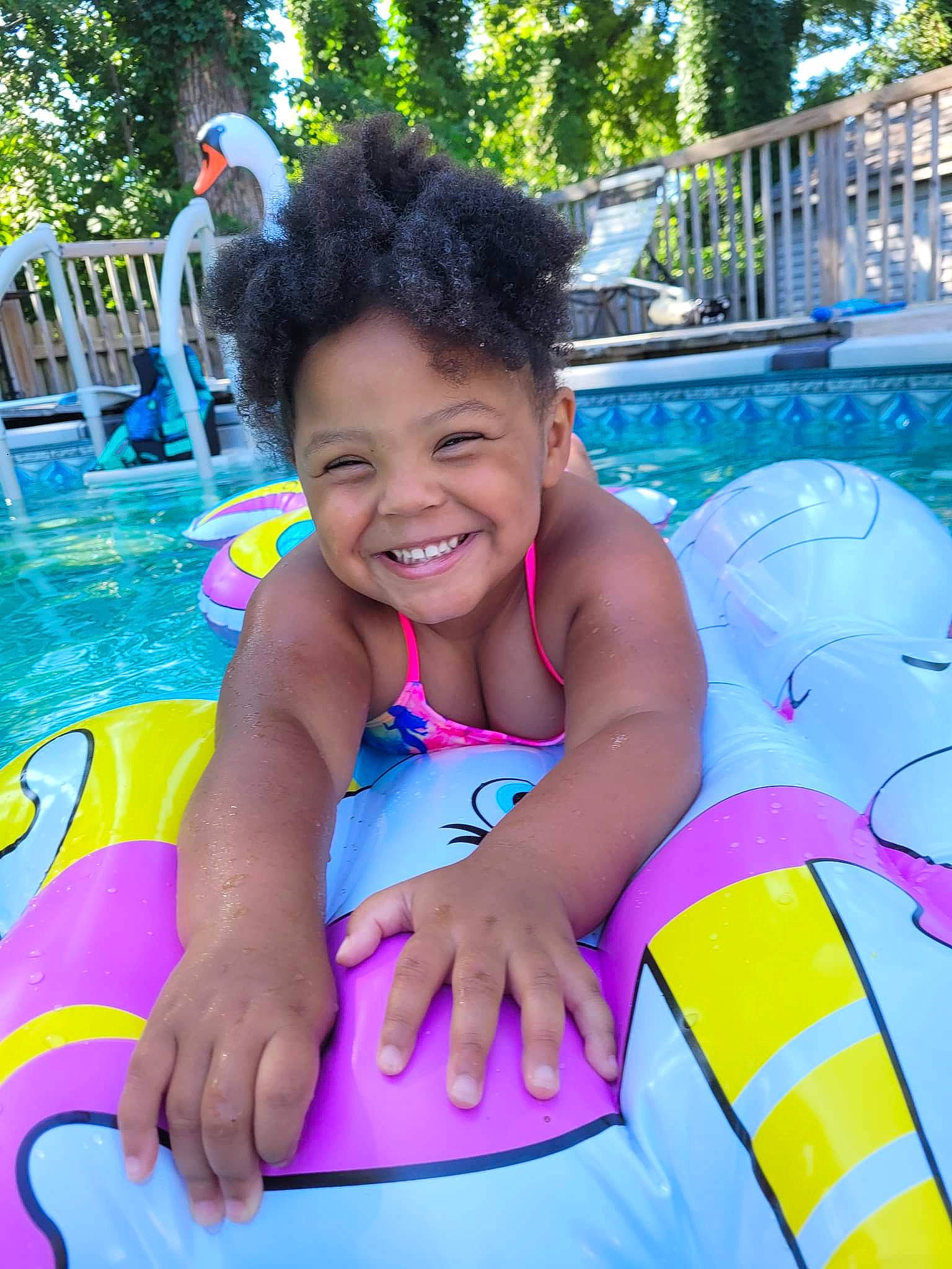 Ariyanna is registered to the contest to win money with this photo: aqua, baby_float, blue, child, fun, green, happy, inflatable, joy, leisure, outdoor_recreation, person, personal_protective_equipment, pink, plant, recreation, smile, summer, swimming_pool, toddler