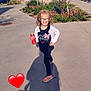 Ashley participe au concours pour gagner de l'argent avec cette photo : child, girl, glasses, soda_can, outdoor, sunny, shadow, building, tree, sidewalk, plants, smiling, casual_clothing, sandals, happy, pose, nature, daylight, urban, heart_emoji
