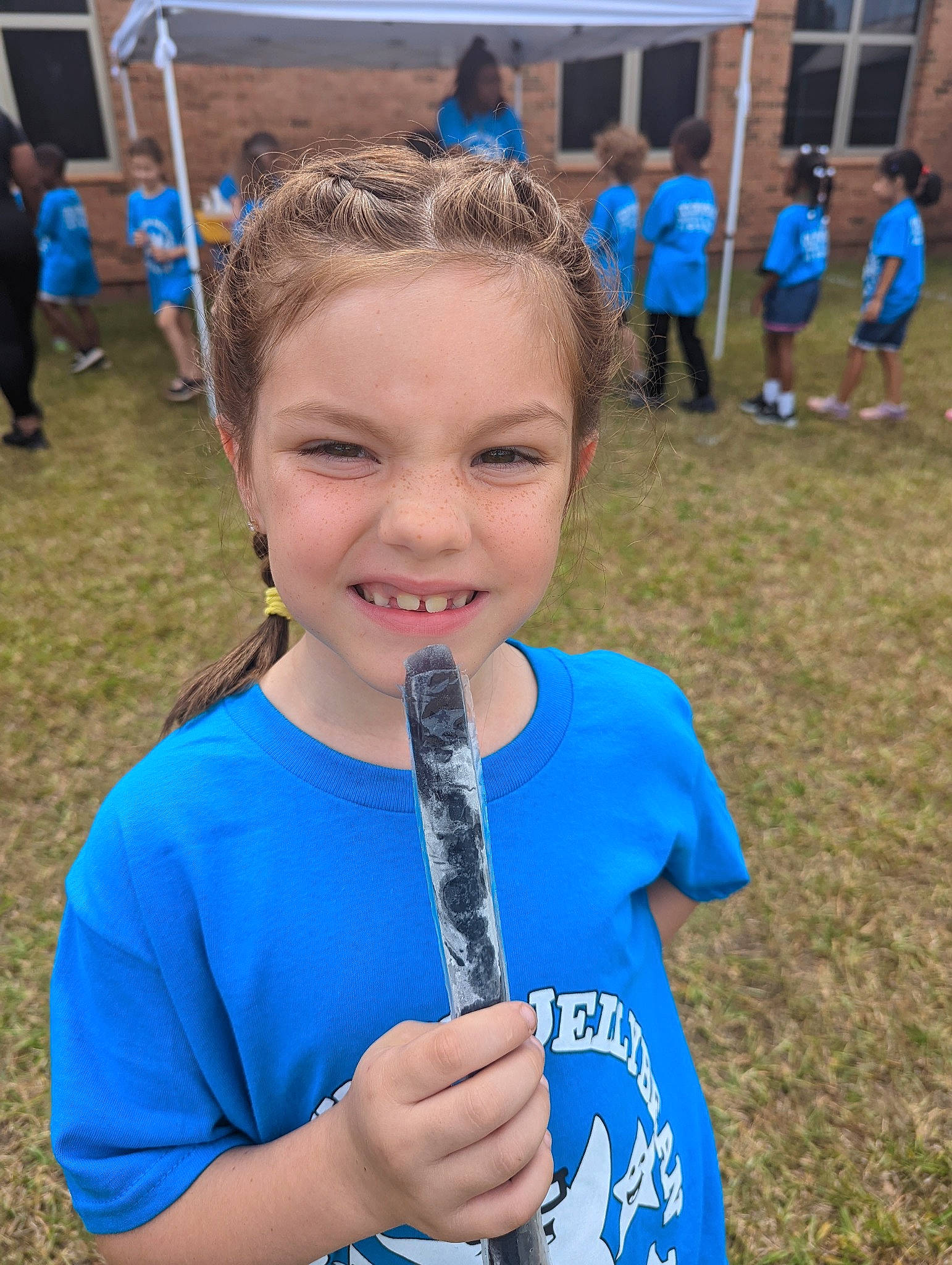 Elia is registered to the contest to win money with this photo: blue, child, competition_event, electric_blue, event, fun, grass, happy, joy, leisure, person, plant, play, recreation, shorts, smile, soil, sports_uniform, sunglasses, t_shirt