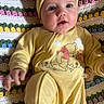 Meadow Rose is registered to the contest to win money with this photo: baby, infant, yellow_onesie, headband, pink_bow, crocheted_blanket, colorful_blanket, cute, chubby_cheeks, face, hand, foot, pacifier, lying_down, indoors, portrait, child, person, soft_lighting, casual_clothing