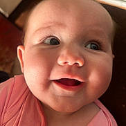 Meadow Rose is registered to the contest to win money with this photo: baby, close_up, smile, face, child, infant, pink_clothing, eyes, cheerful, indoors, skin, head, person, cute, happy, portrait, young_child, baby_girl, expression, mouth_open