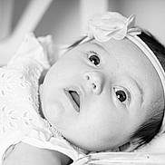 Stella participe au concours pour gagner de l'argent avec cette photo : baby, infant, headband, flower, close_up, black_and_white, portrait, wide_eyes, curious, soft_lighting, delicate, cute, face, skin, young_child, lying_down, expression, innocence, newborn, child