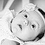 baby, infant, headband, flower, close_up, black_and_white, portrait, wide_eyes, curious, soft_lighting, delicate, cute, face, skin, young_child, lying_down, expression, innocence, newborn, child