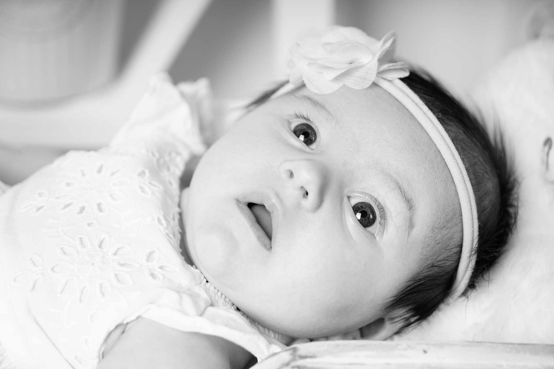Stella participe au concours pour gagner de l'argent avec cette photo : baby, infant, headband, flower, close_up, black_and_white, portrait, wide_eyes, curious, soft_lighting, delicate, cute, face, skin, young_child, lying_down, expression, innocence, newborn, child